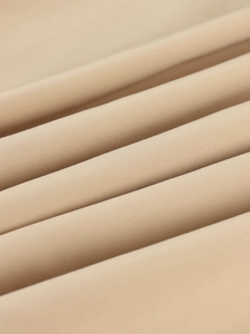 Macro view of beige twill fabric texture showing premium weave detail for long trench coats