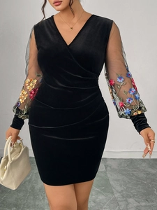 Close-up of sheer mesh sleeves with colorful floral embroidery on a black velvet dress