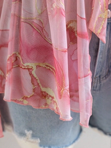 Close-up of pink marble print sheer mesh top with ruffled edges and lightweight texture