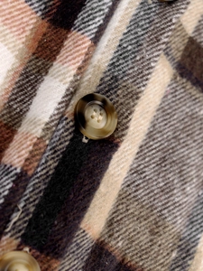 Macro shot of retro plaid jacket fabric and textured amber-colored four-hole button