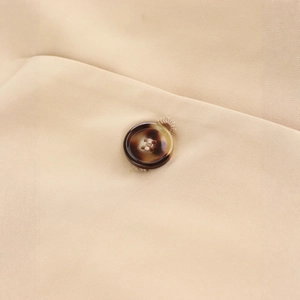 Close-up of brown tortoiseshell button and premium khaki fabric on a long trench coat