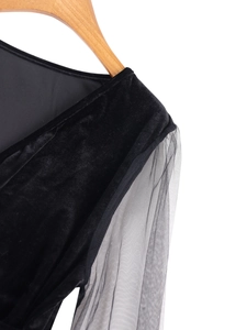 Close-up of elegant black velvet shoulder with sheer mesh sleeve on a wooden hanger