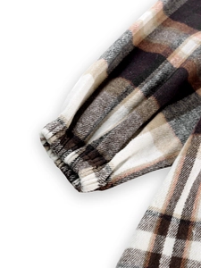 Detailed close-up of brown plaid cotton fabric with elastic cuffs on a loose jacket