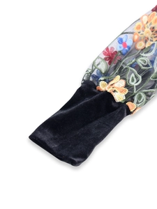 Detail of black velvet sleeve featuring intricate multi-color floral embroidery on mesh