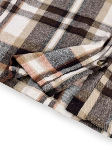 Macro detail of plaid cotton jacket hem with precise stitching and brown button
