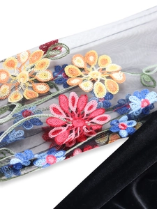 Detail of floral embroidery on black mesh and velvet fabric of the V-neck dress