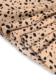 Close-up of leopard print dress hem featuring black polka dots on beige fabric