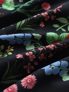 Macro shot of floral print fabric with red and pink flowers on dark background