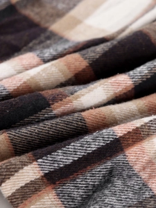 Close-up of brushed plaid flannel fabric in brown and beige tones for autumn jacket