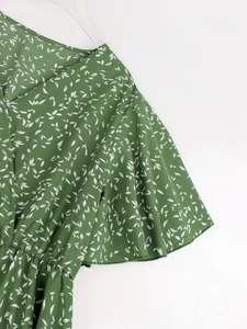 Détail de la robe fleurie verte avec manches à volants, col en V et taille élastique