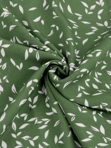 Vue macro de la texture du tissu en mousseline verte avec motif de feuilles blanches