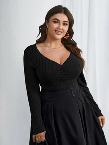 Dettaglio del top nero in maglia a coste con scollo a V e gonna con bottoni decorativi