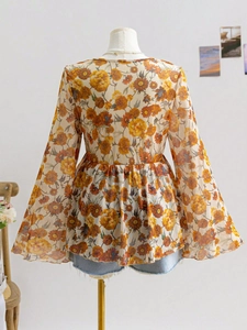 Detail of floral chiffon blouse with bell sleeves and orange retro vintage patterns