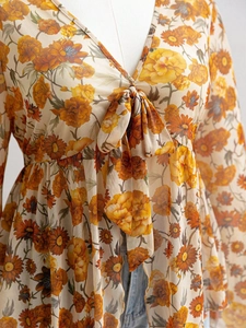 Detail of V-neck floral print mesh top featuring a delicate bow tie and empire waistline
