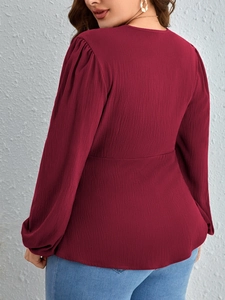 Elegant wine red V-neck blouse with puff sleeves and textured fabric on female model