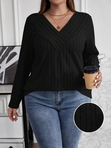 Detail of plus size black ribbed knit top featuring a stylish crossover V-neckline design