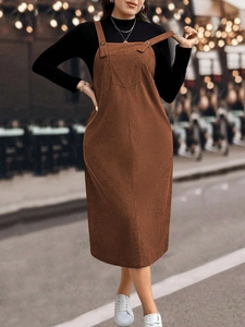 Women's brown corduroy overall dress in loose mid-length style with front patch pockets