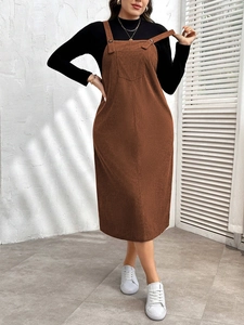 Detail of brown corduroy pinafore dress with button straps and front decorative pocket