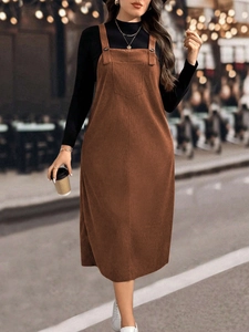 Detail of a brown corduroy overall dress with large chest pocket and button straps