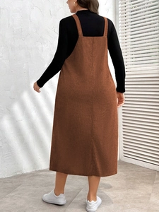 Back view of brown corduroy pinafore dress with slit detail and black turtleneck