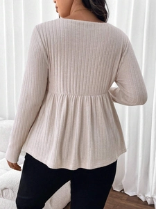 Elegant plus size cream ribbed knit top featuring long sleeves and ruffled hem design