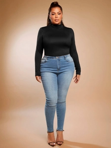 Slim fit black turtleneck long sleeve top for women paired with washed blue jeans
