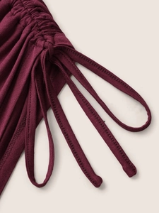 Detail of burgundy top featuring elegant side ruching and adjustable drawstrings