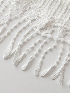 Elegant white knit top with fringe tassels and intricate hollow patterns