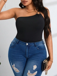Détail du body noir à une épaule avec anneau métallique et jean denim déchiré bleu