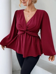 Détail de la blouse bordeaux à col en V avec taille nouée et manches lanternes