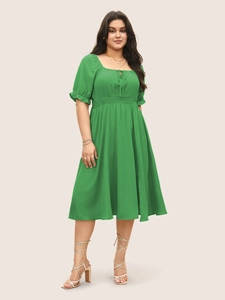 Détails de la robe verte avec manches bouffantes, col carré, laçage et taille smockée