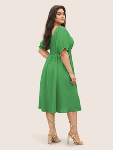 Détail de robe verte grande taille avec manches bouffantes et coupe taille haute