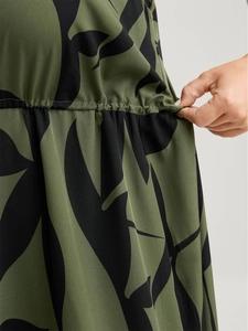 Detail of elastic drawstring waist with leaf print on olive green midi dress fabric