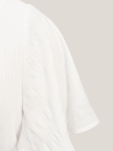 Detail view of white high-waisted dress showing ruffled sleeves and crinkled fabric texture