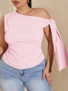 Detail of pink one-shoulder top featuring a large decorative bow tie on the shoulder