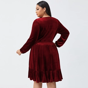 Detail of burgundy velvet dress featuring long sleeves and ruffled hem with waist cut