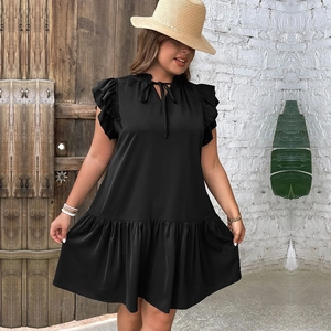 Detail of black tiered dress featuring ruffle sleeves, V-neck tie, and breathable fabric