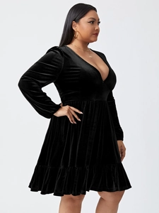 Detailed texture of black velvet party dress featuring a deep V-neck and pleated hemline