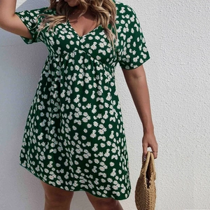 Gros plan d'une robe verte à col en V avec des imprimés de marguerites et taille haute