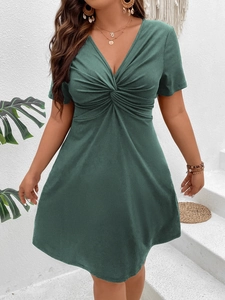 Detail of V-neck and twist knot design on a dark green ribbed knit A-line short dress