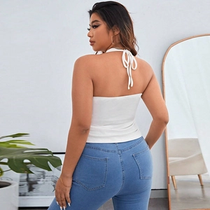Detail of white halter neck backless top paired with high waist skinny jeans