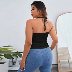 Detail of black halter ribbed knit top with open back and classic blue slim fit jeans