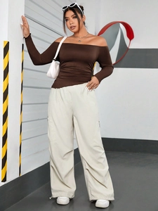Brown off-shoulder long sleeve top paired with cream cargo pants in a street style shot