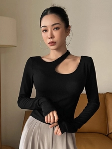 Détail du haut en maille noire avec découpe asymétrique à l'épaule et texture côtelée