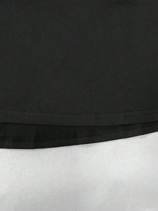 Detailed close-up of double-stitched hem and high-density knit fabric on a black dress