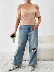 Women's apricot cold shoulder V-neck T-shirt paired with ripped denim blue jeans