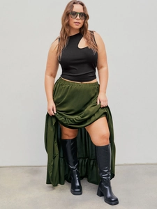 Slim fit sleeveless black knit top paired with a green satin maxi skirt and boots