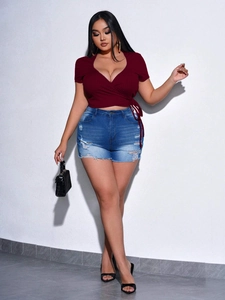Detail of burgundy V-neck slim knit top with wrap design and high-waist denim shorts