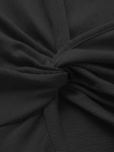 Dettaglio del tessuto nero testurizzato con nodo centrale e pieghe decorative