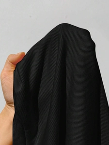 Détail de la texture du tissu en maille côtelée noire montrant des rayures verticales